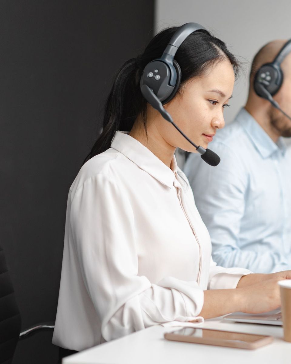 Nhân viên tổng đài đeo tai nghe làm việc cùng đồng nghiệp tại phòng Call Center
