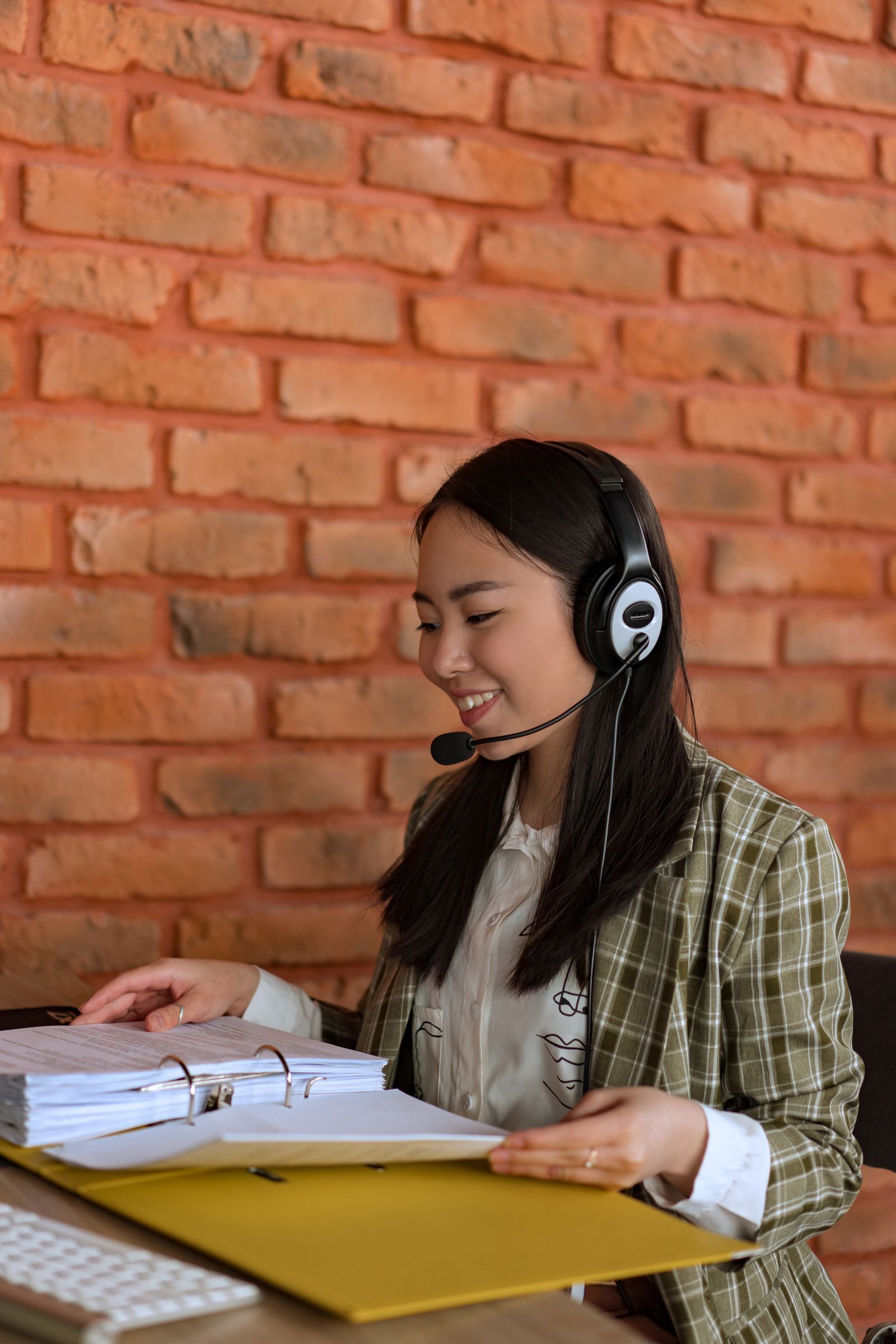 Nhân viên tư vấn mỉm cười, đeo tai nghe và ghi chú hồ sơ khách hàng